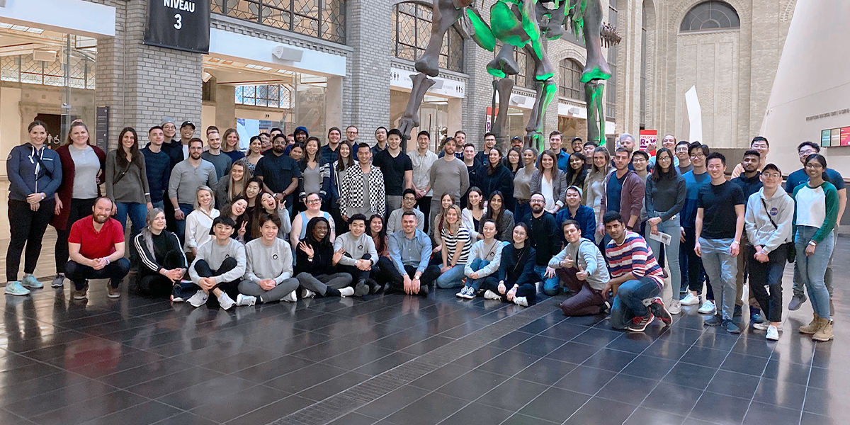 group photo of more than 30 people posing together in the atrium of a museum